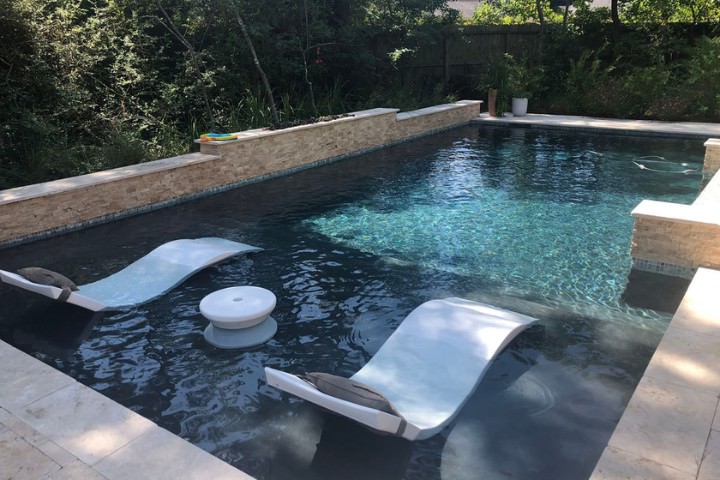 Modern custom pool with relaxing built-in tanning lounge ledges